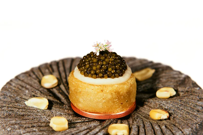 Small masa tart topped with caviar and a flower at Californios