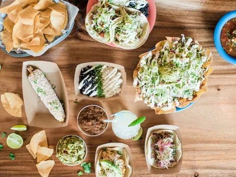 Overhead spread of tacos, elote, loaded nachos, chips, salsa and a margarita at El Rayo Taqueria in Portland, Maine