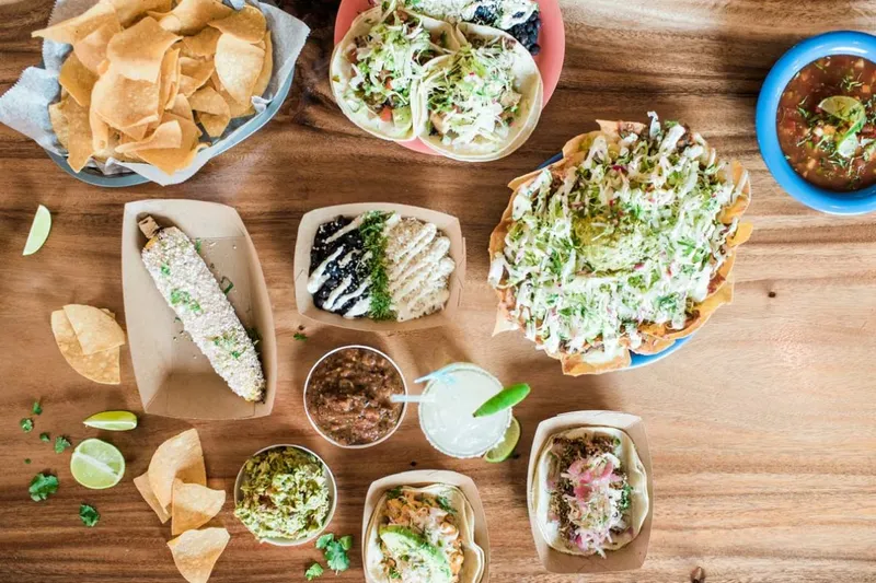 Overhead spread of tacos, elote, loaded nachos, chips, salsa and a margarita at El Rayo Taqueria in Portland, Maine