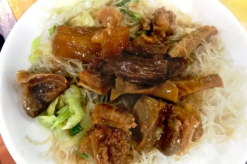 Braised beef brisket and tendon over rice vermicelli with lettuce in a white bowl at Big Fun Café in Quincy