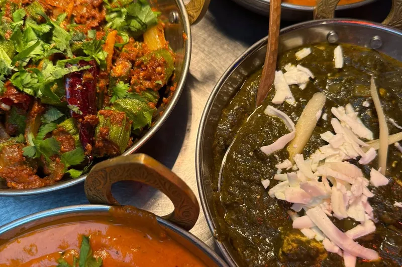 Karahis of curry, saag and chana served together at Midnight Temple