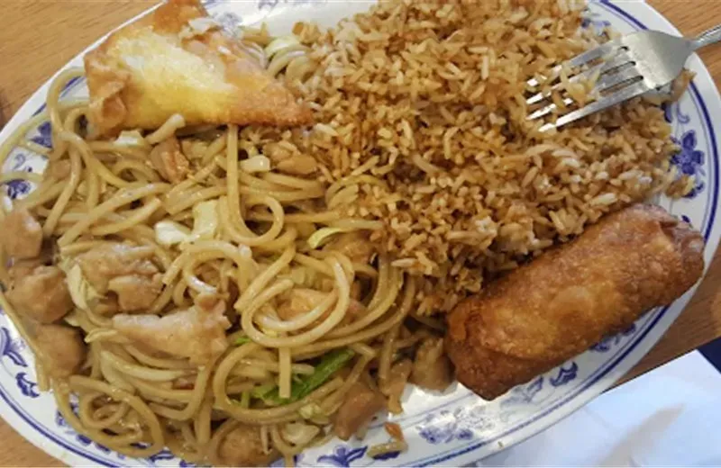 A combination plate of chicken chow mein, fried rice, an egg roll, and a crab rangoon on a classic blue-and-white plate at PongPong Chinese Cuisine in Phoenix