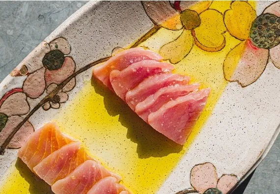Sliced raw fish crudo with olive oil on a floral-patterned plate at Oberlin in Providence