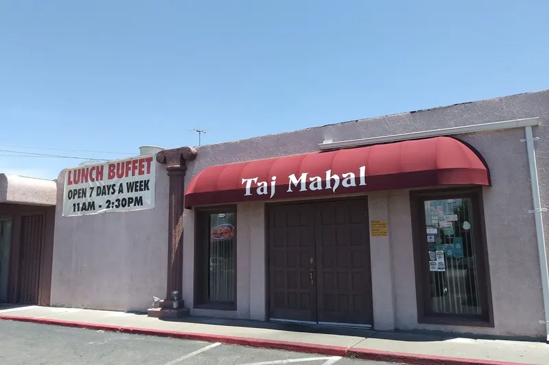 Exterior storefront of Taj Mahal Cuisine of India on Carlisle Blvd NE, Albuquerque, with a red awning, OPEN sign, and lunch buffet banner