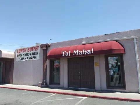 Exterior storefront of Taj Mahal Cuisine of India on Carlisle Blvd NE, Albuquerque, with a red awning, OPEN sign, and lunch buffet banner