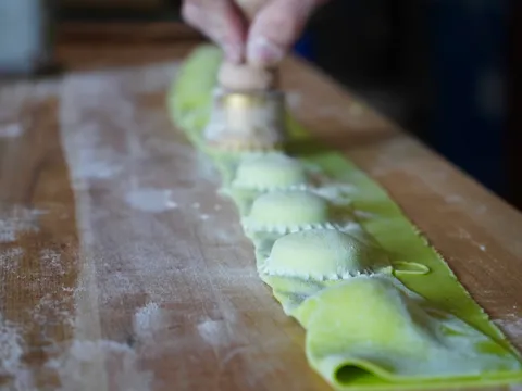 Fresh green ravioli being cut by hand at Gumba in Portland
