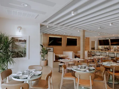 Bright Pijja Palace dining room with round set tables, wood chairs, and a long bar