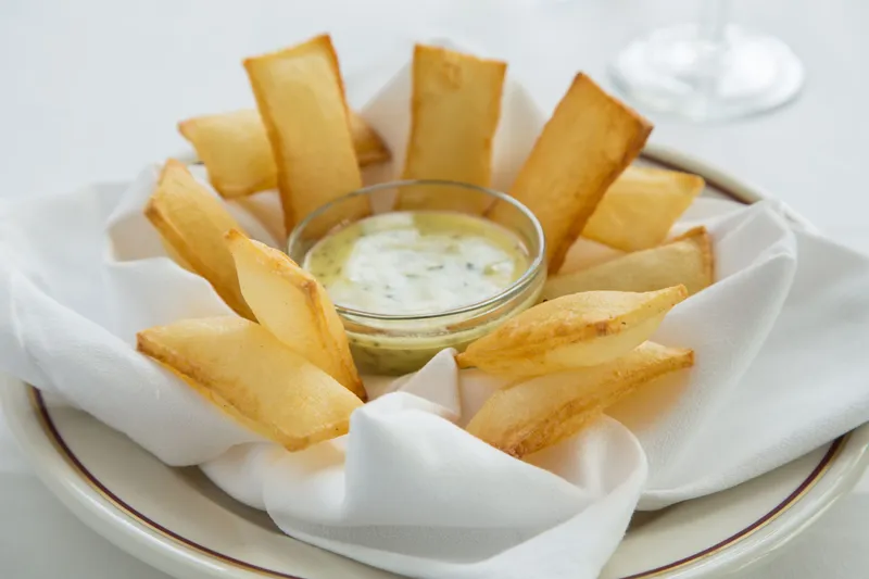 Arnaud's souffle potatoes (pommes souffles) served with a dish of bearnaise sauce on white linen