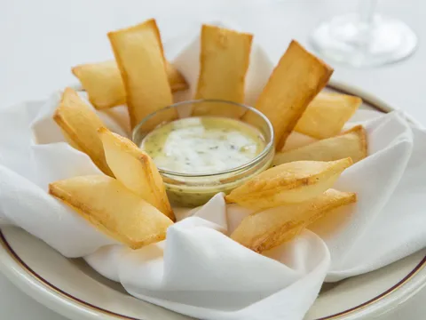 Arnaud's souffle potatoes (pommes souffles) served with a dish of bearnaise sauce on white linen