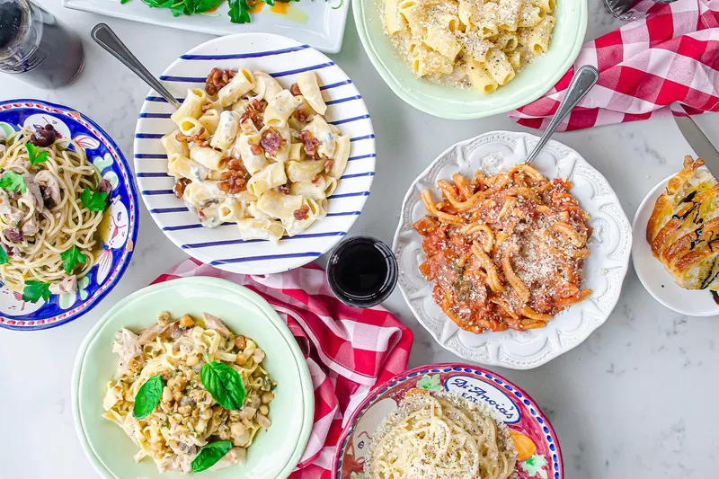 Overhead spread of house-made pasta dishes in DiAnoia's Eatery hand-painted ceramic bowls with focaccia and wine in Pittsburgh