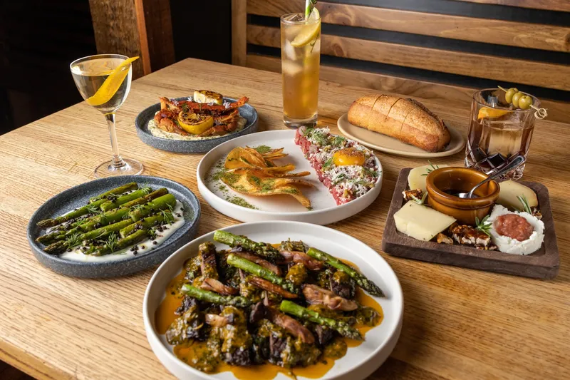 Spread of Spanish tapas including beef tartare, soft-shell crab, grilled asparagus, a cheese board, bread and cocktails at Morcilla in Pittsburgh