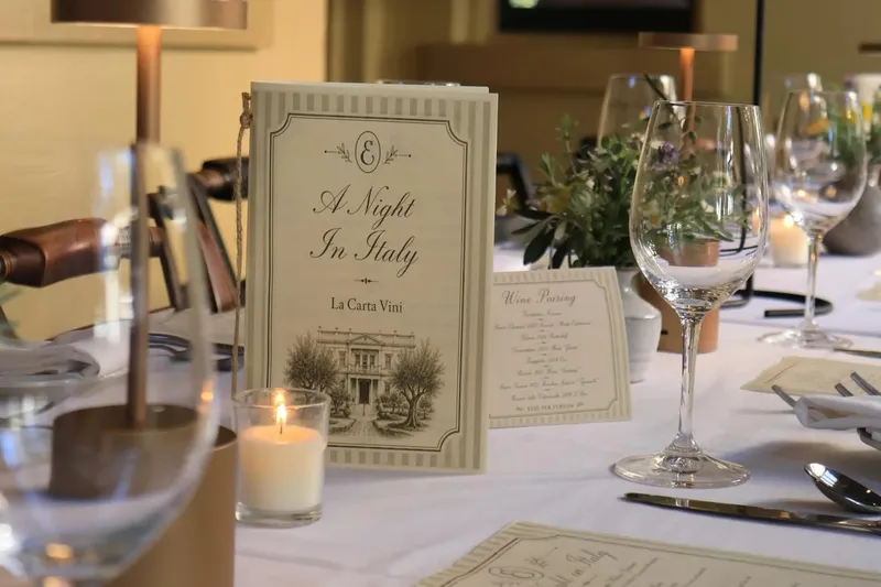 Candlelit dining room table set with white linen, wine glasses, and menu cards at Elizabeth on 37th in Savannah