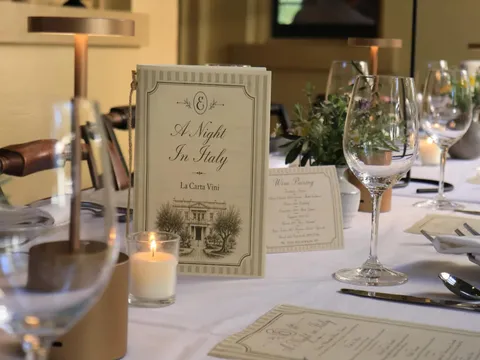 Candlelit dining room table set with white linen, wine glasses, and menu cards at Elizabeth on 37th in Savannah