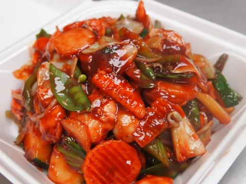Sweet-and-sour chicken with vegetables in a white takeout container at Three Happiness Express.