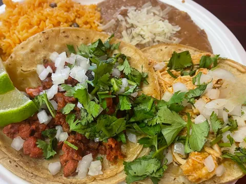 Plate of al pastor and chicken street tacos with Mexican rice and refried beans at Tacos Don Jose