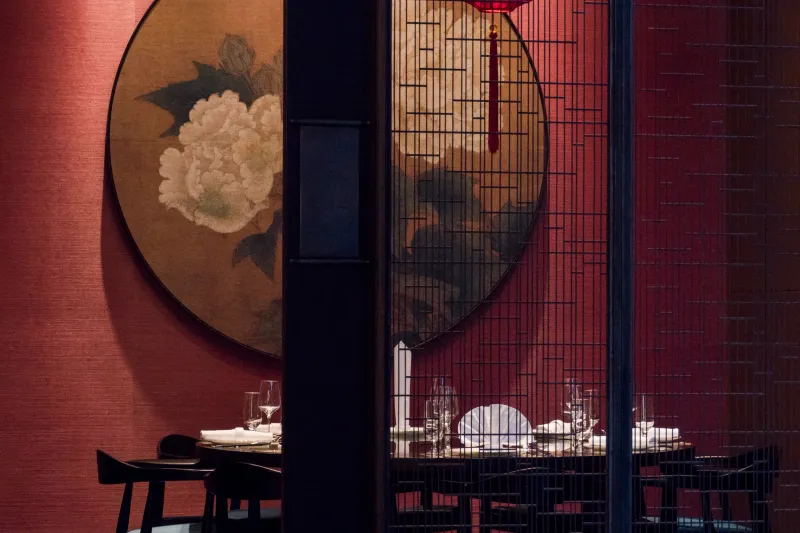 Dining room with red walls, a peony painting and lattice screens at Meizhou Dongpo, Century City
