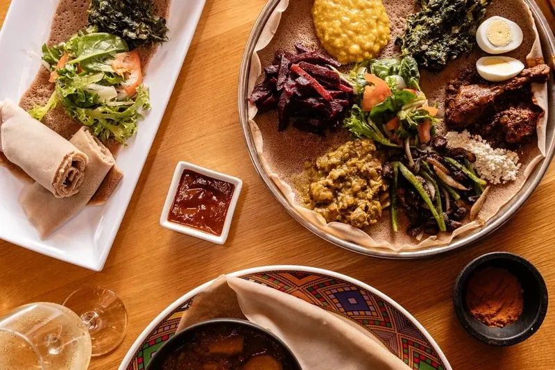 Ethiopian combination platters on injera with stews, greens and salads, plus a spice tray, at Demera in Chicago