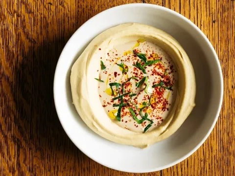 Bowl of classic tahini hummus topped with olive oil, Aleppo pepper and herbs at Saba in New Orleans