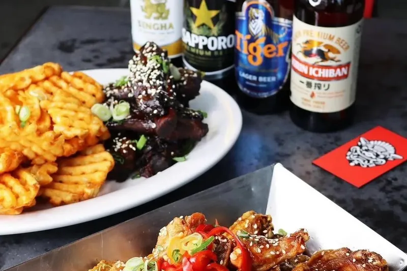 Platter of sesame-glazed Peking sticky wings with waffle fries and bottled Asian beers at The Peterboro in Detroit's Historic Chinatown