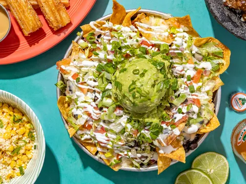 Overhead spread of loaded nachos topped with guacamole, street-corn elote, churros and carnitas at Taco Boy in Charleston, South Carolina