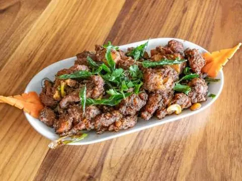 Bawarchi Andhra-style curry-leaf chicken fry plated with fresh herbs