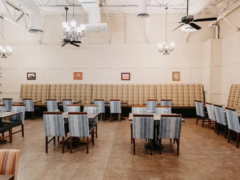 Dining room with banquette seating, striped chairs and chandeliers at India Oven