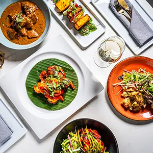 Overhead spread of Modern Indian dishes at Karma Modern Indian, including curry, grilled kebabs, seafood and a shredded salad