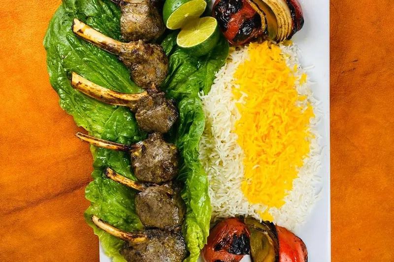 Rack of lamb kabob at Shamshiri Grill in Westwood, Los Angeles, plated with saffron-topped basmati rice and grilled tomato, onion and pepper on romaine