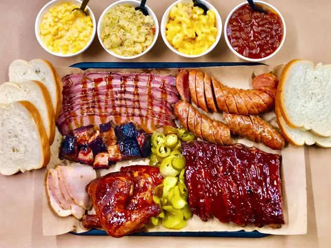 Slap's BBQ sampler platter with sliced brisket, burnt ends, sausage, ribs, smoked chicken, ham, pickles and sides